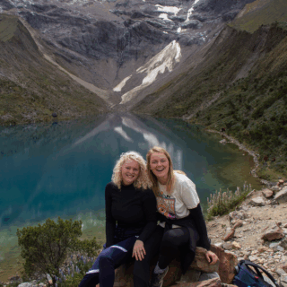 amigas_sonriendo_junto_a_lago_y_montaña_nevada-friends_smiling_next_to_lake_and_snowy_mountain