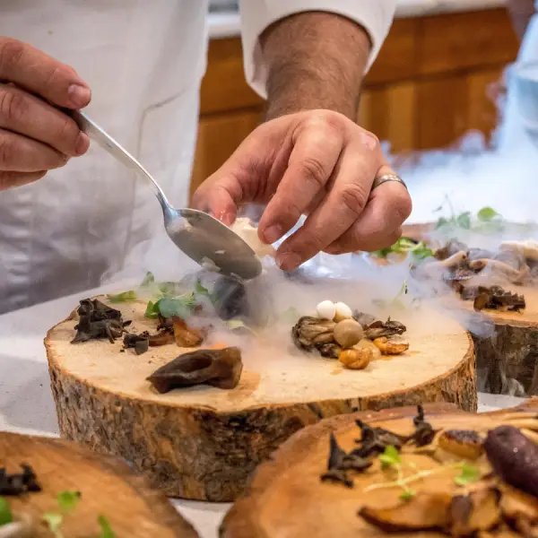 https://www.peru-reservations.com/wp-content/uploads/2025/10/chef_emplatando_comida_con_humo_en_troncos-chef_plating_food_with_smoke_on_wood_logs.jpg