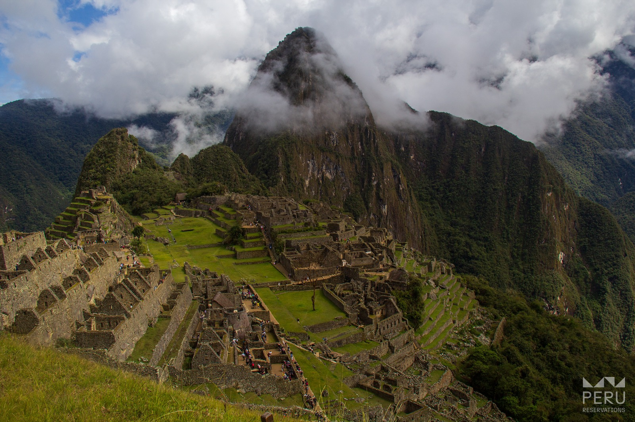 https://www.peru-reservations.com/wp-content/uploads/2025/10/grupo_de_turistas_en_machu_picchu_montanas_con_nubes-group_of_tourists_in_machu_picchu_mountains_with_clouds.png