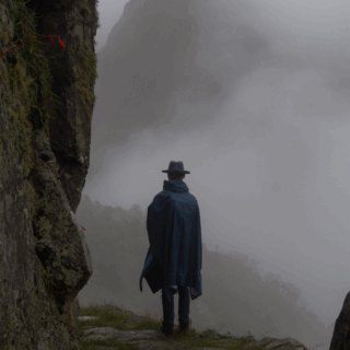 hombre_con_sombrero_y_capa_en_montañas_neblina-man_with_hat_and_cape_in_misty_mountains