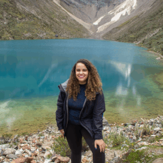 mujer_sonriendo_frente_a_lago_azul_de_montaña-woman_smiling_in_front_of_blue_mountain_lake