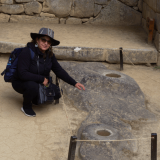 mujer_turista_apuntando_roca_tallada_en_machu_picchu-woman_tourist_pointing_at_carved_rock_in_machu_picchu