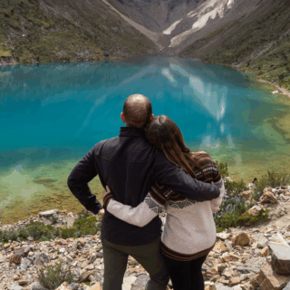 pareja_abrazada_viendo_lago_turquesa_y_montañas-embracing_couple_seeing_turquoise_lake_and_mountains