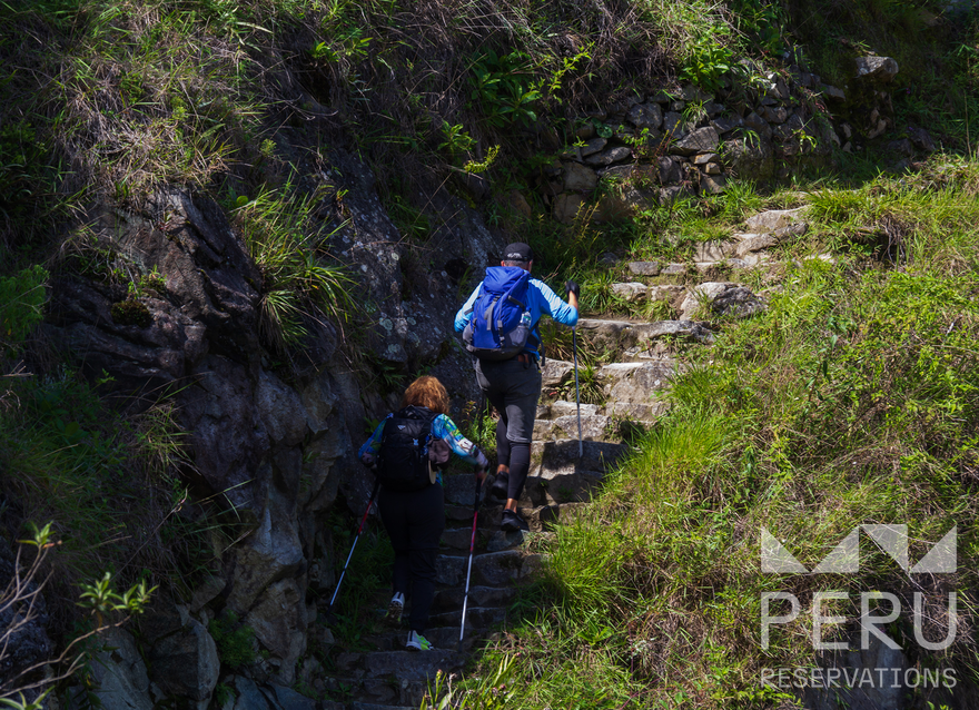 https://www.peru-reservations.com/wp-content/uploads/2025/10/pareja_subiendo_escalones_de_piedra_en_sendero_montanoso-couple_climbing_stone_steps_on_mountain_trail.png