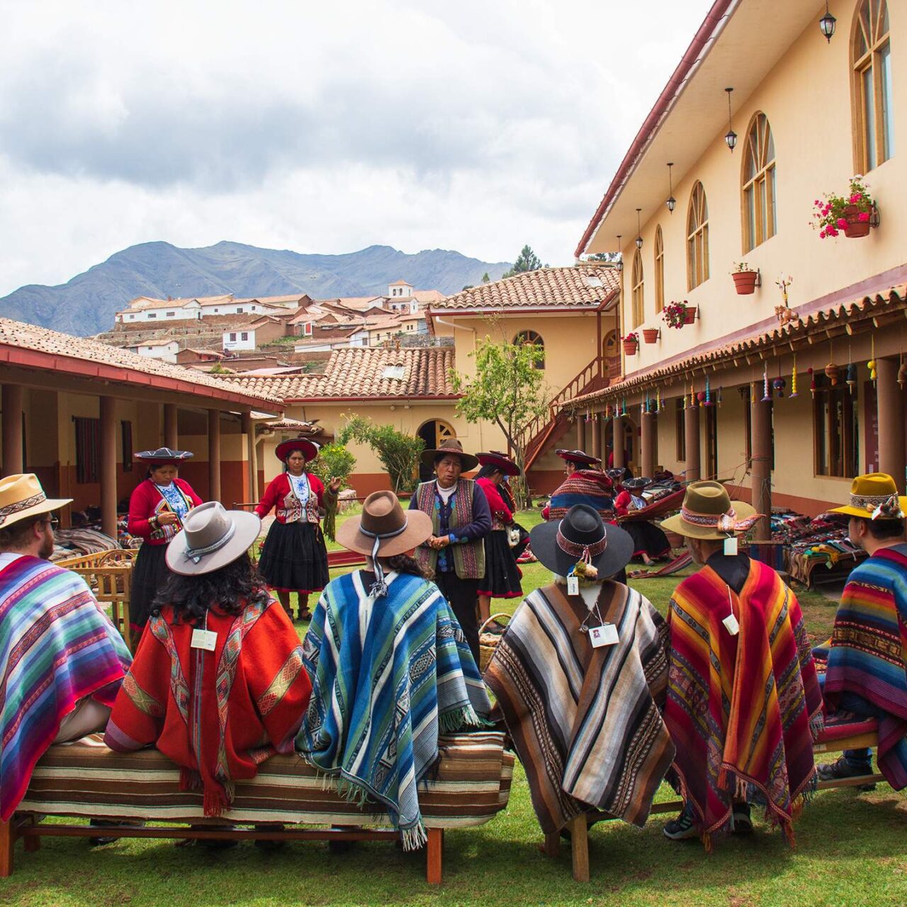 https://www.peru-reservations.com/wp-content/uploads/2025/10/personas_con_ponchos_en_patio_de_pueblo_andino-people_with_ponchos_in_andean_village_courtyard-1280x1280.jpg
