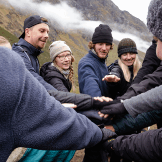 grupo_de_excursionistas_uniendo_manos_en_montañas-group_of_hikers_joining_hands_in_mountains