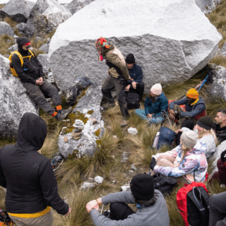 grupo_de_personas_descansando_entre_rocas_grandes_y_pasto-group_of_people_resting_among_large_rocks_and_grass