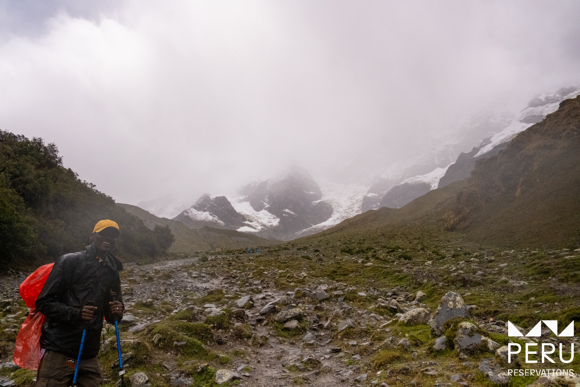 Male hiker in snowy cloudy mountains