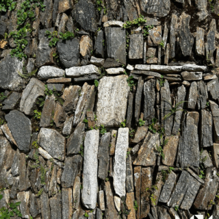 pared_de_piedra_con_cruz_y_plantas_verdes-stone_wall_with_cross_and_green_plants