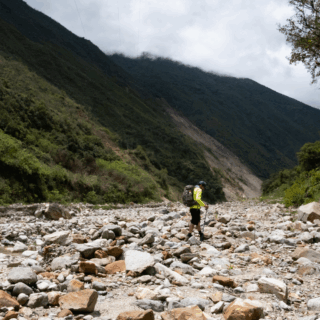 senderista_en_lecho_de_río_rocoso_entre_montañas-hiker_in_rocky_riverbed_between_mountains