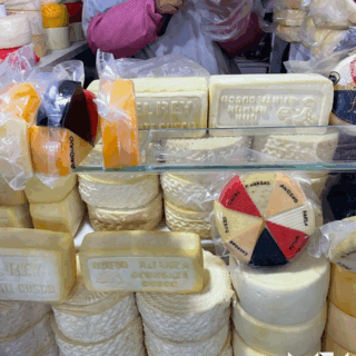 vendedora_cortando_quesos_en_puesto_de_mercado-female_vendor_cutting_cheeses_in_market_stall